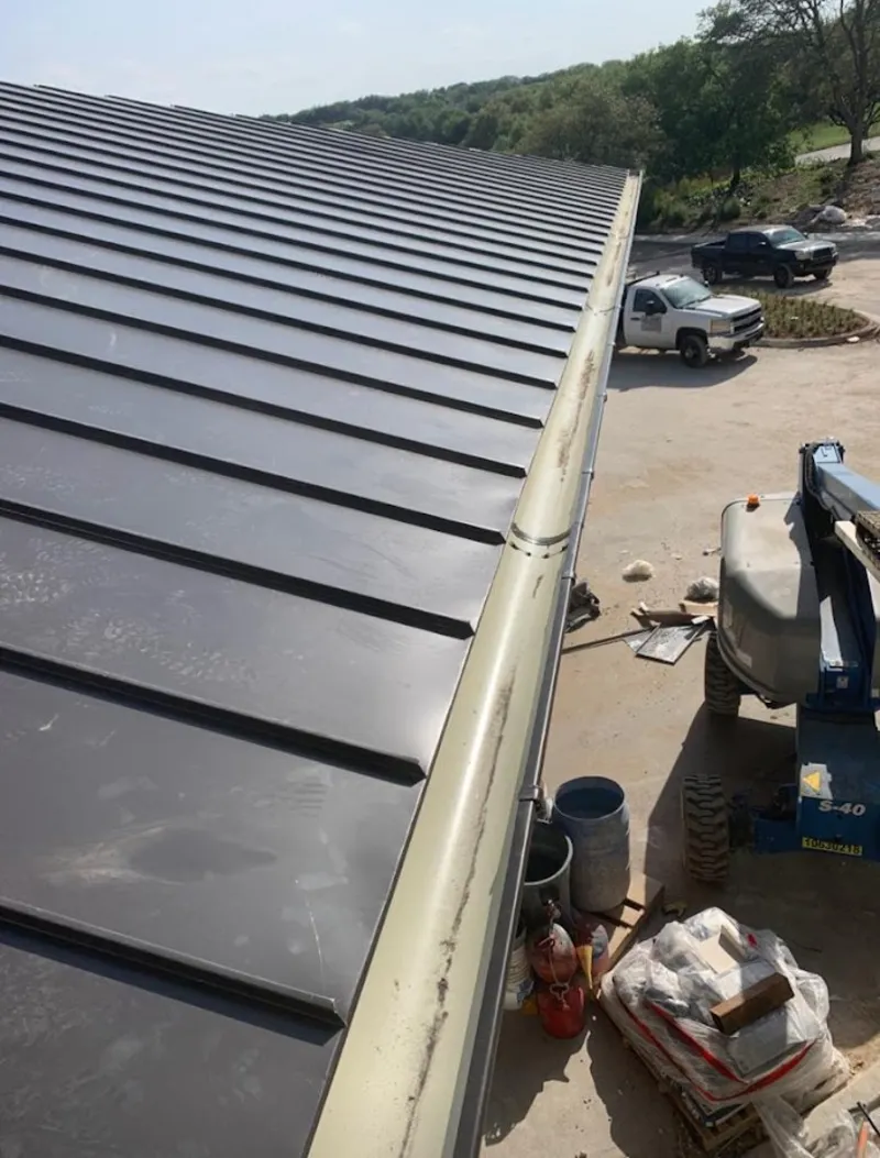 Standing seam panel and gutter detail on a metal roofing jobsite in Hutto